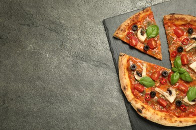 Tasty pizza with basil, olives and tomato on grey textured table, top view. Space for text