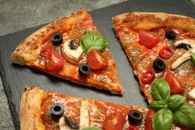 Tasty pizza with basil, olives and tomato on grey table, closeup