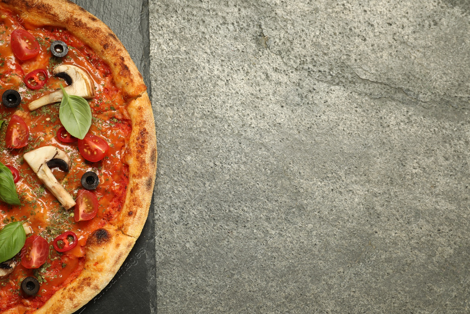 Photo of Tasty pizza with basil, olives and tomato on grey textured table, top view. Space for text