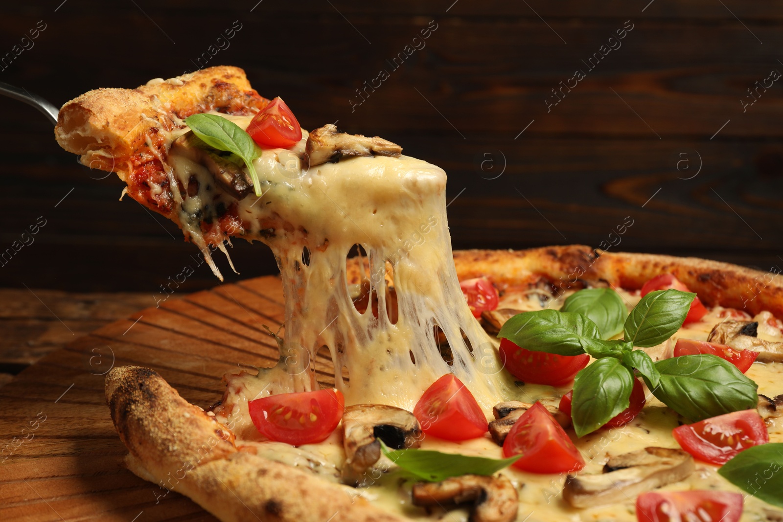 Photo of Taking piece of tasty pizza with melted cheese at wooden table, closeup