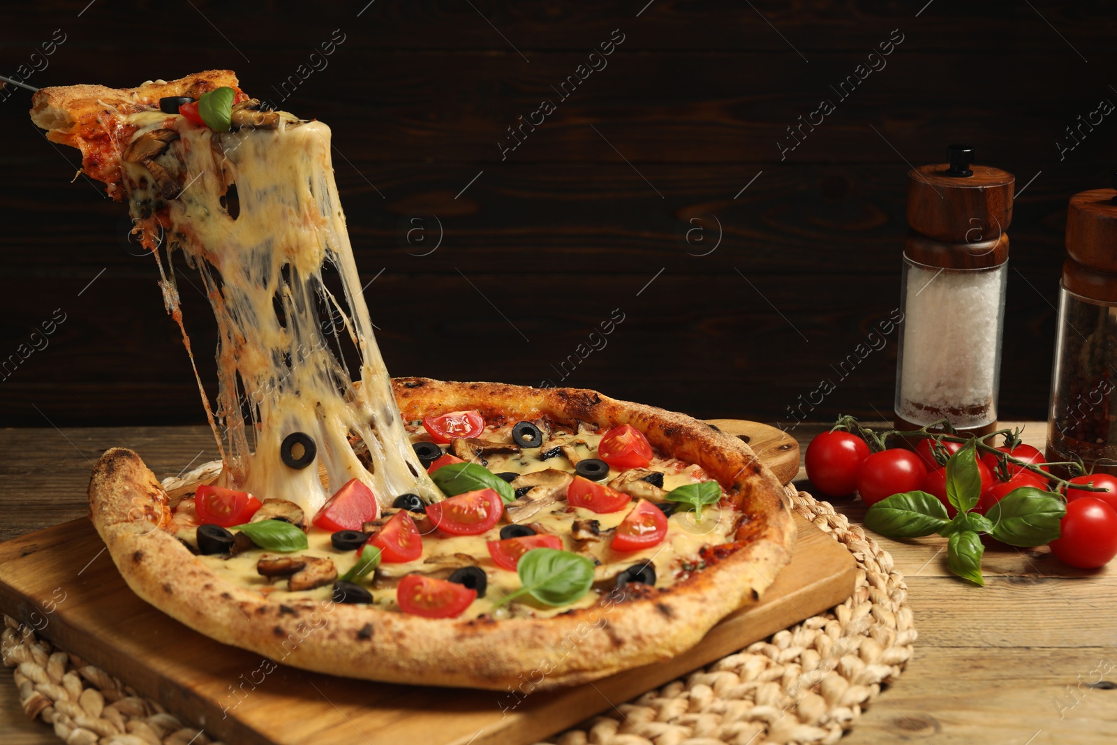 Photo of Taking piece of tasty pizza with melted cheese at wooden table, closeup