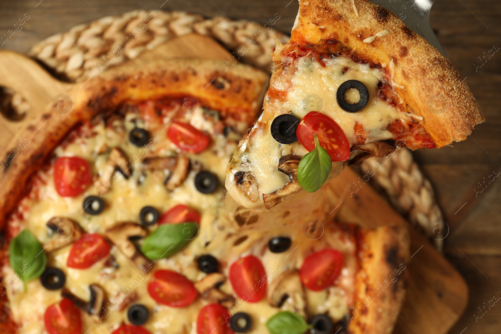 Photo of Taking piece of tasty pizza with melted cheese at wooden table, top view