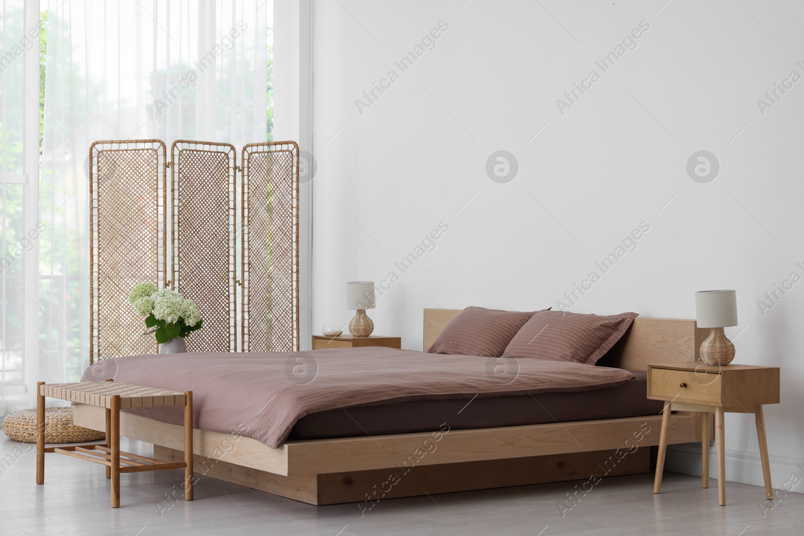 Photo of Folding screen, comfortable bed, ottoman and bedside tables in room