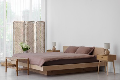 Folding screen, comfortable bed, ottoman and bedside tables in room