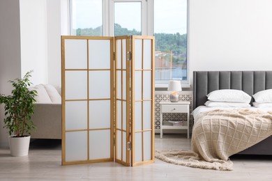 Photo of Folding screen, bed and houseplant in bedroom