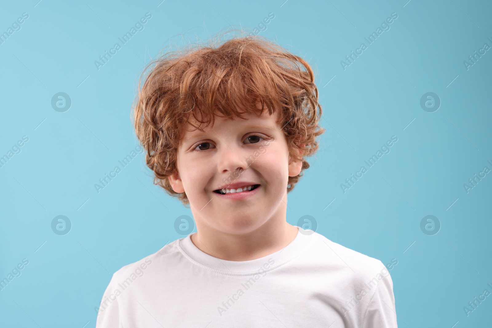 Photo of Portrait of cute little boy on light blue background