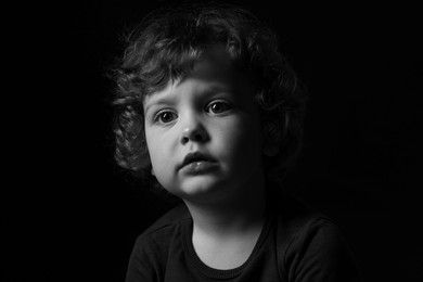 Photo of Portrait of cute little boy on dark background. Black and white effect