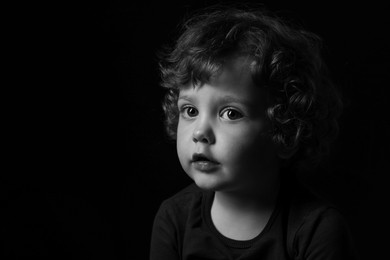 Portrait of cute little boy on dark background, space for text. Black and white effect