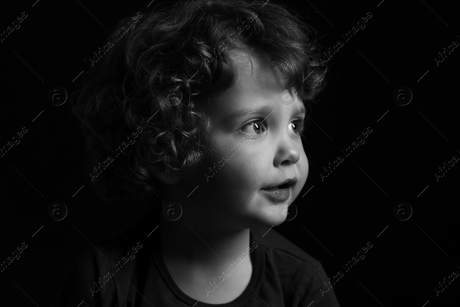 Photo of Portrait of cute little boy on dark background. Black and white effect