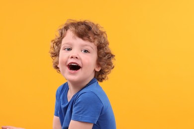 Portrait of emotional little boy on yellow background, space for text