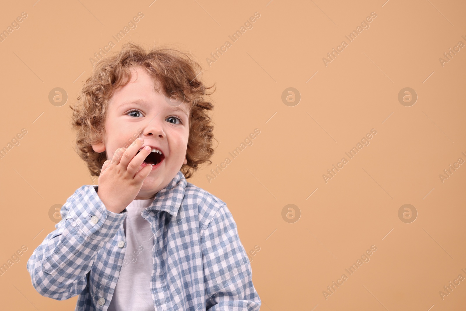 Photo of Portrait of cute little boy on beige background, space for text