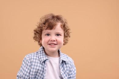 Portrait of cute little boy on beige background, space for text