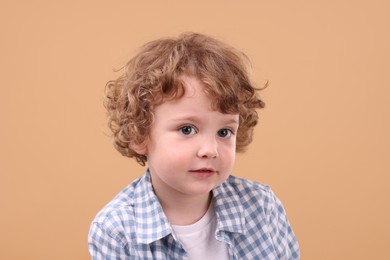 Portrait of cute little boy on beige background