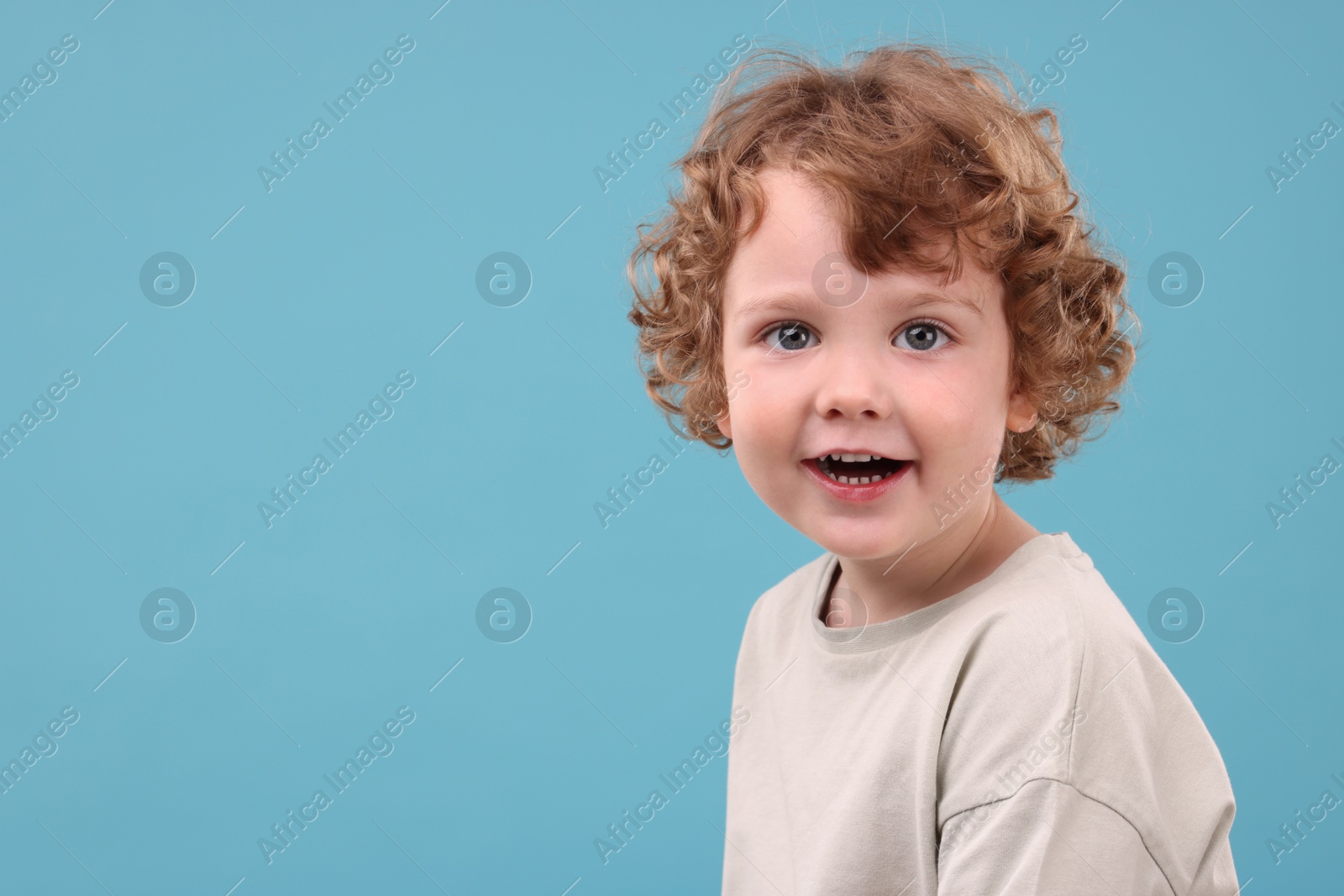 Photo of Portrait of cute little boy on light blue background, space for text