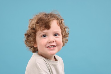 Photo of Portrait of cute little boy on light blue background, space for text