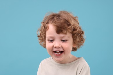 Portrait of cute little boy on light blue background