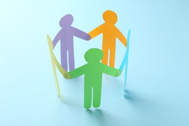 Photo of Equality concept. Paper human figures on light blue background, closeup