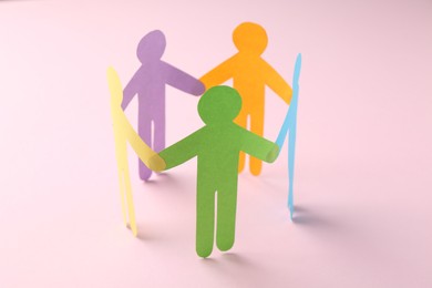 Photo of Equality concept. Paper human figures on pink background, closeup