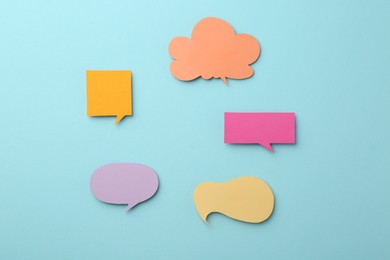 Photo of Equality concept. Different paper speech bubbles on light blue background, flat lay