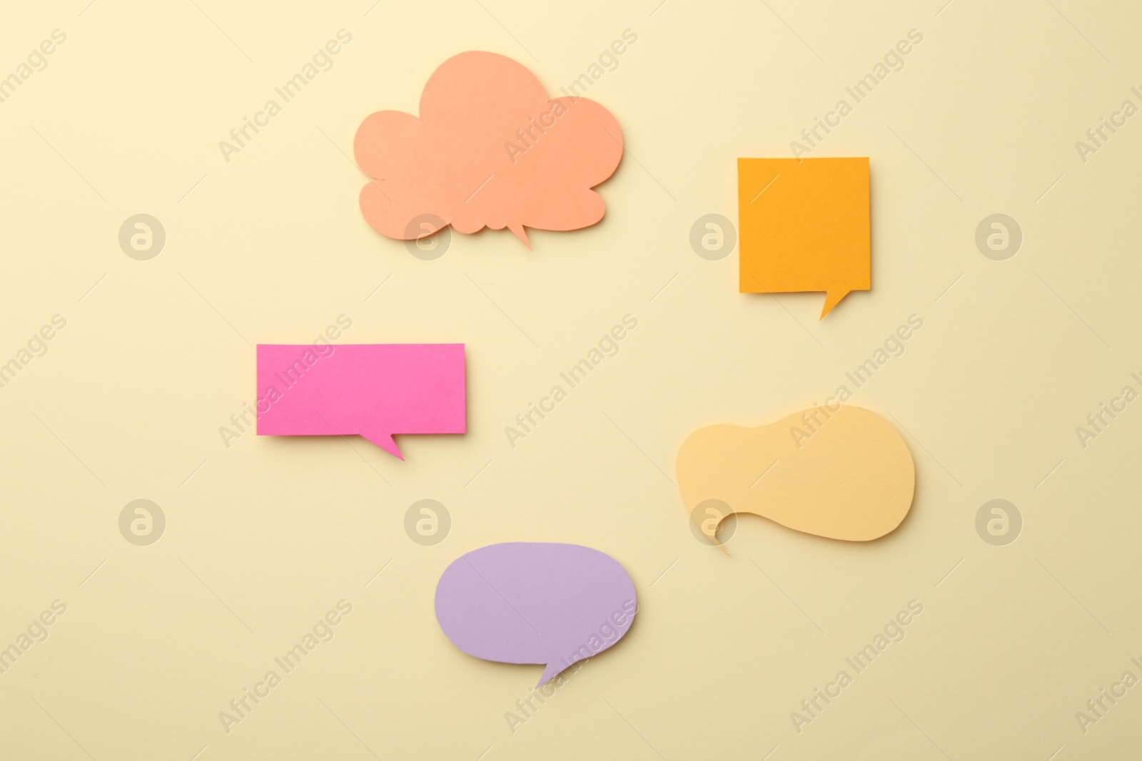 Photo of Equality concept. Different paper speech bubbles on beige background, flat lay