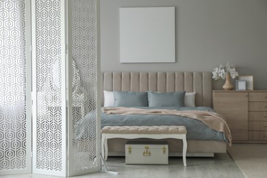 Photo of Folding screen, mirror and comfortable bed in bedroom. Interior design