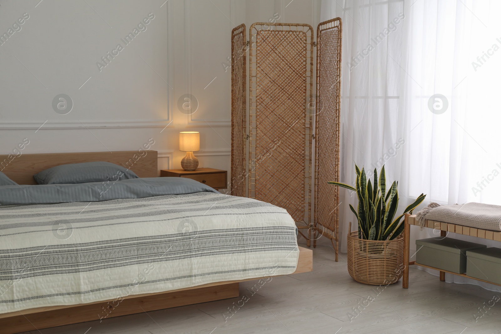 Photo of Stylish bedroom with double bed and beautiful green houseplant. Modern interior