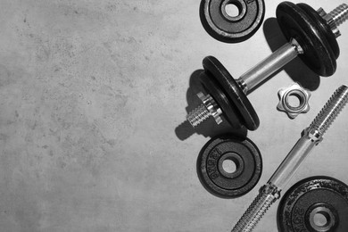 Photo of Barbell and parts of one on grey floor, flat lay. Space for text