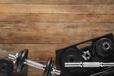 Barbell and parts of one on wooden floor, flat lay. Space for text