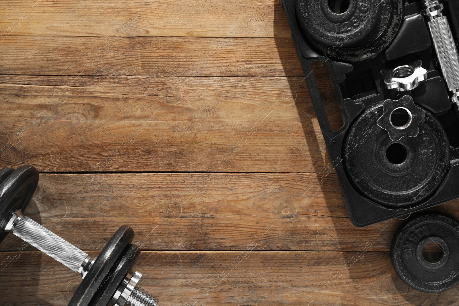 Photo of Barbell and parts of one on wooden floor, flat lay. Space for text