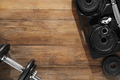Photo of Barbell and parts of one on wooden floor, flat lay. Space for text