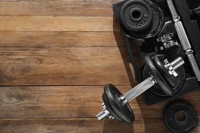 Photo of Barbell and parts of one on wooden floor, flat lay. Space for text