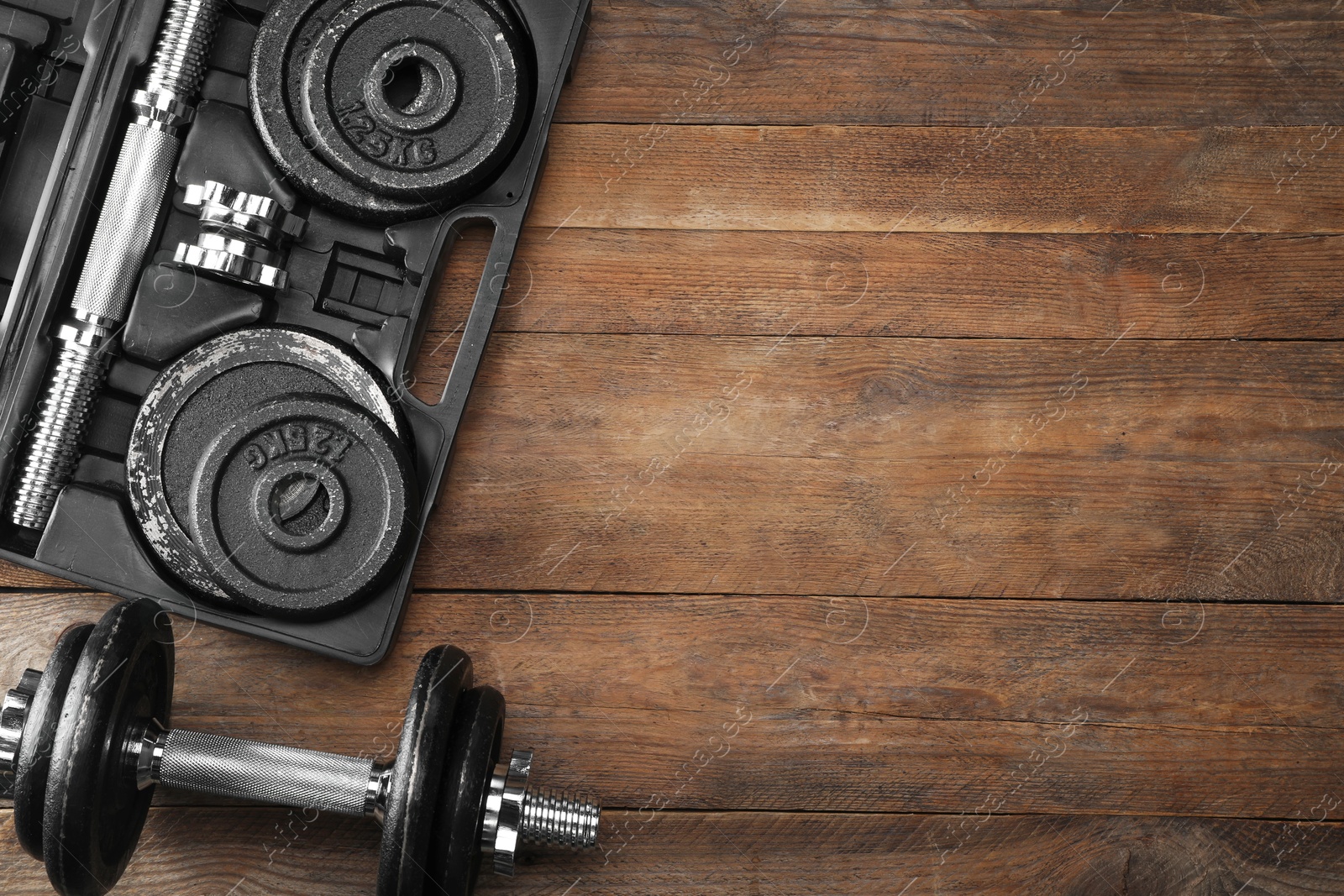 Photo of Barbell and parts of one on wooden floor, flat lay. Space for text