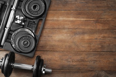 Barbell and parts of one on wooden floor, flat lay. Space for text