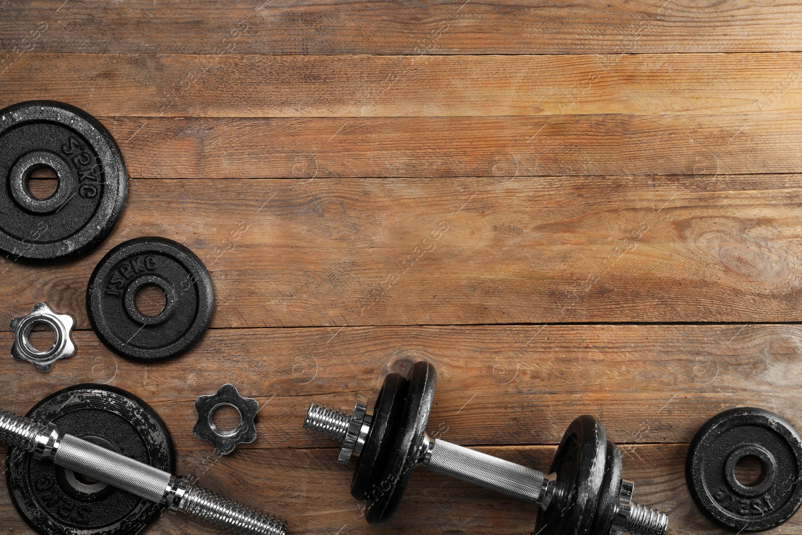 Photo of Barbell and parts of one on wooden floor, flat lay. Space for text