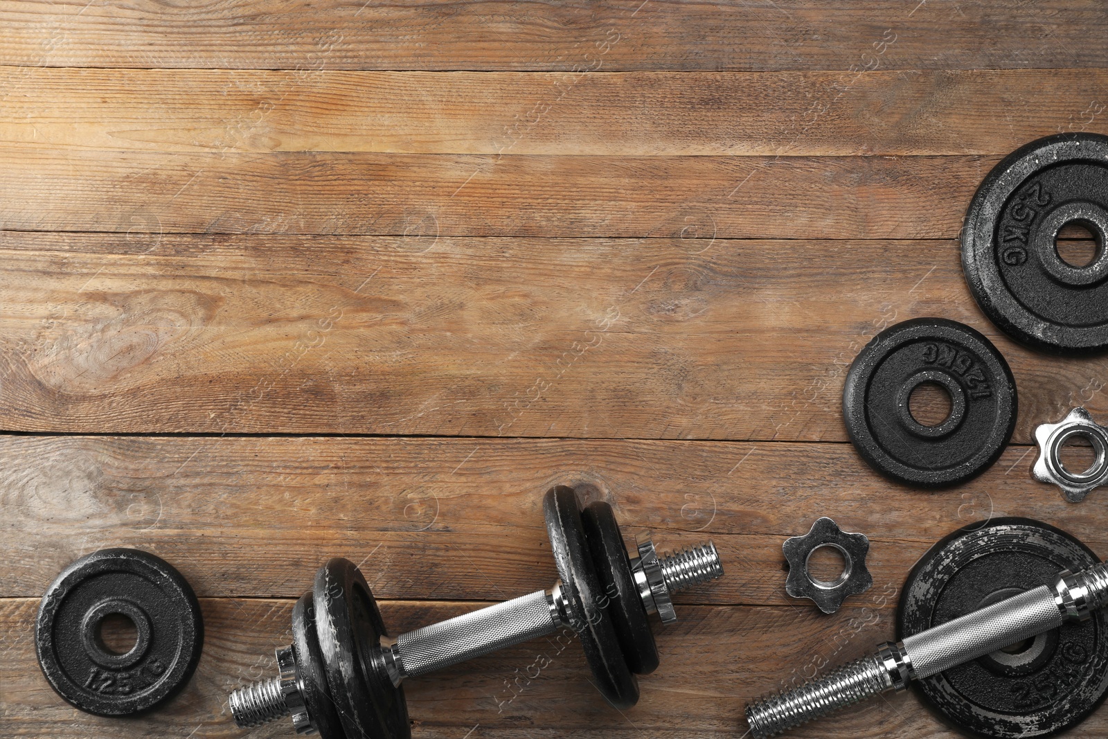 Photo of Barbell and parts of one on wooden floor, flat lay. Space for text