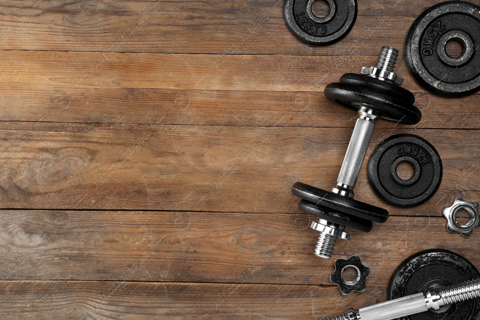 Photo of Barbell and parts of one on wooden floor, flat lay. Space for text