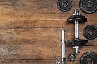 Photo of Barbell and parts of one on wooden floor, flat lay. Space for text