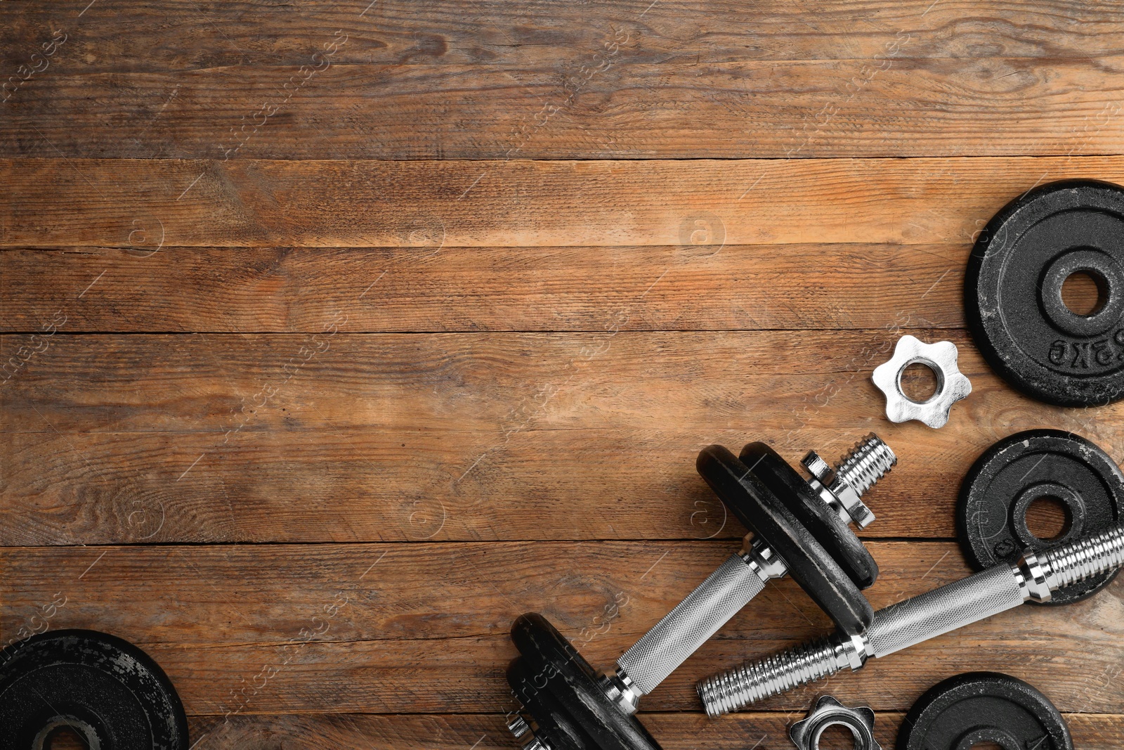 Photo of Barbell and parts of one on wooden floor, flat lay. Space for text