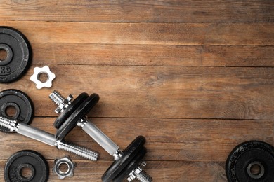 Photo of Barbell and parts of one on wooden floor, flat lay. Space for text