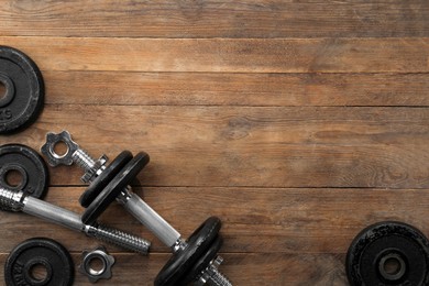 Photo of Barbell and parts of one on wooden floor, flat lay. Space for text