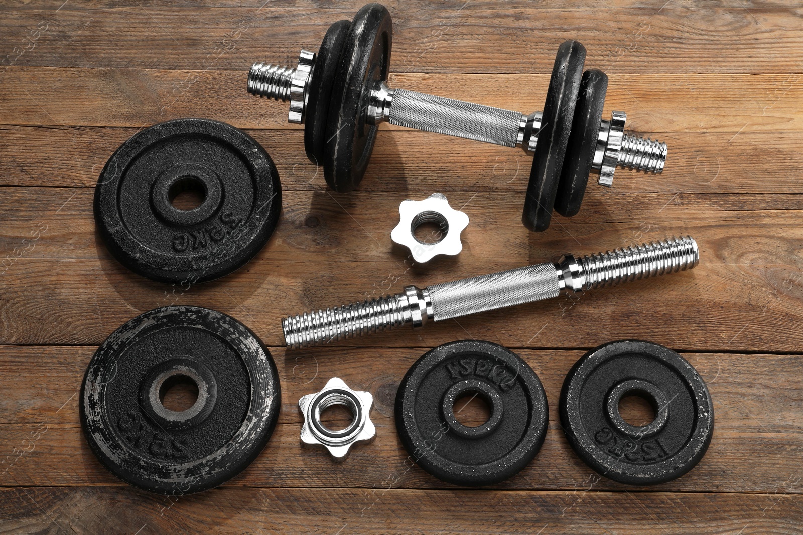 Photo of Barbell and parts of one on wooden floor, flat lay