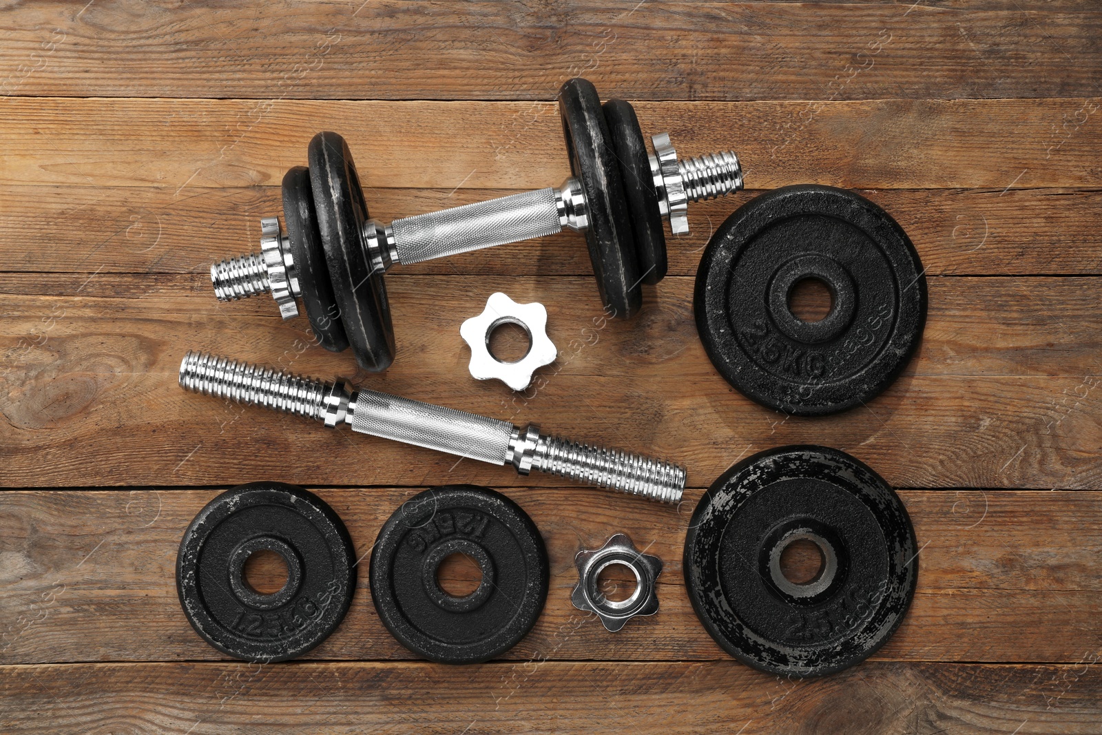 Photo of Barbell and parts of one on wooden floor, flat lay