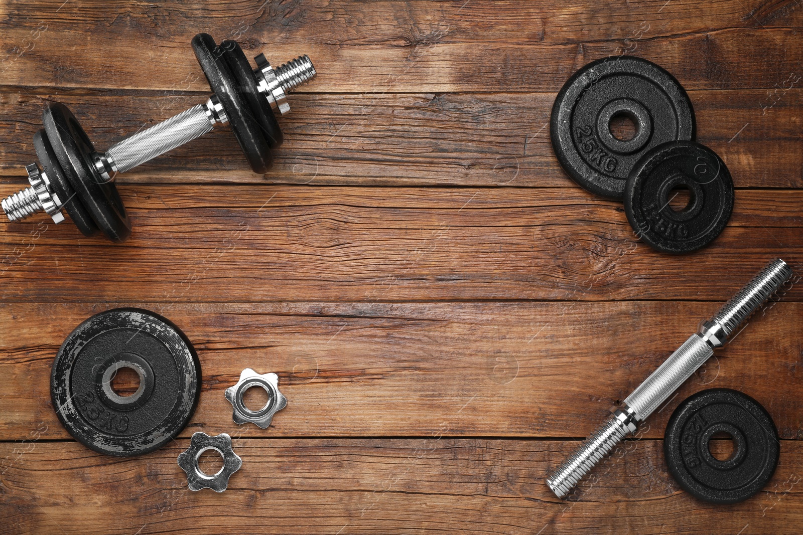 Photo of Barbell and parts of one on wooden floor, flat lay. Space for text