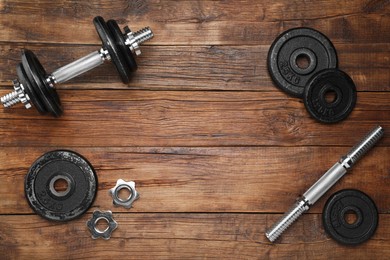 Photo of Barbell and parts of one on wooden floor, flat lay. Space for text