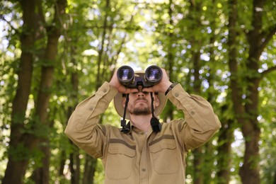 Photo of Forester with binoculars examining plants in forest