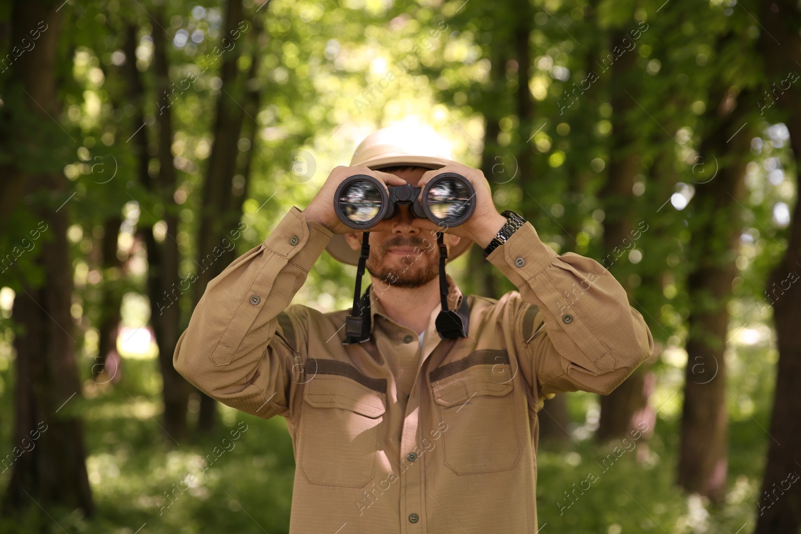 Photo of Forester with binoculars examining plants in forest