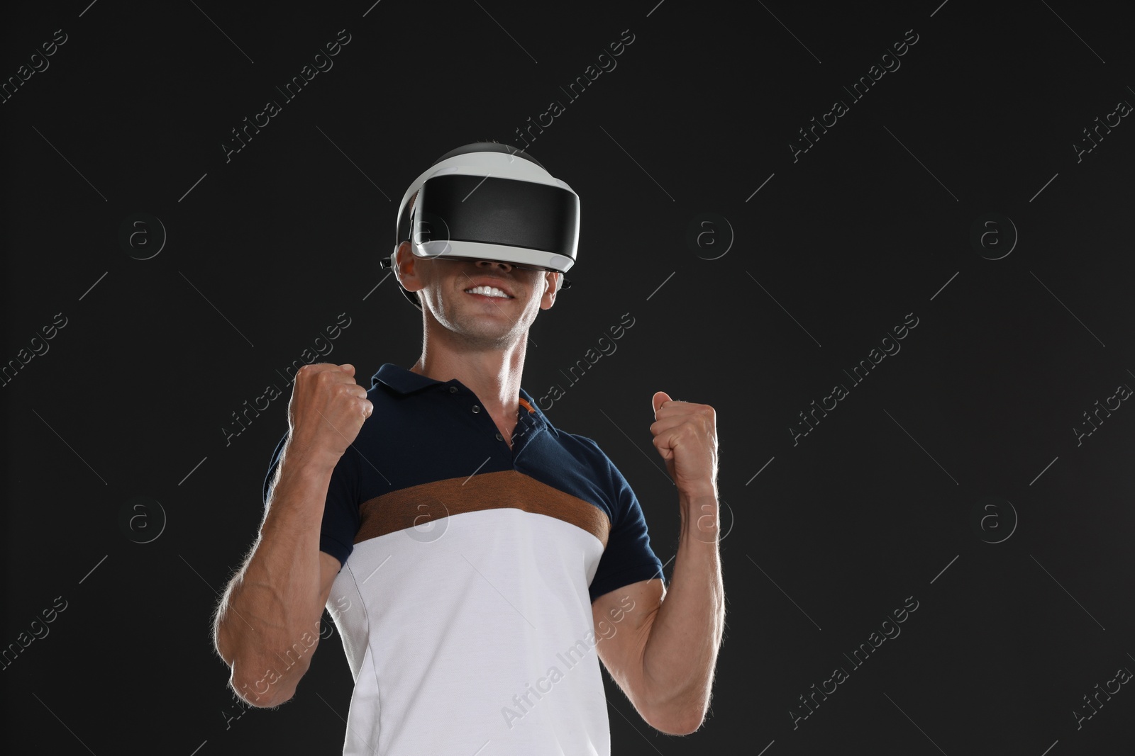 Photo of Smiling man using virtual reality headset on black background, space for text