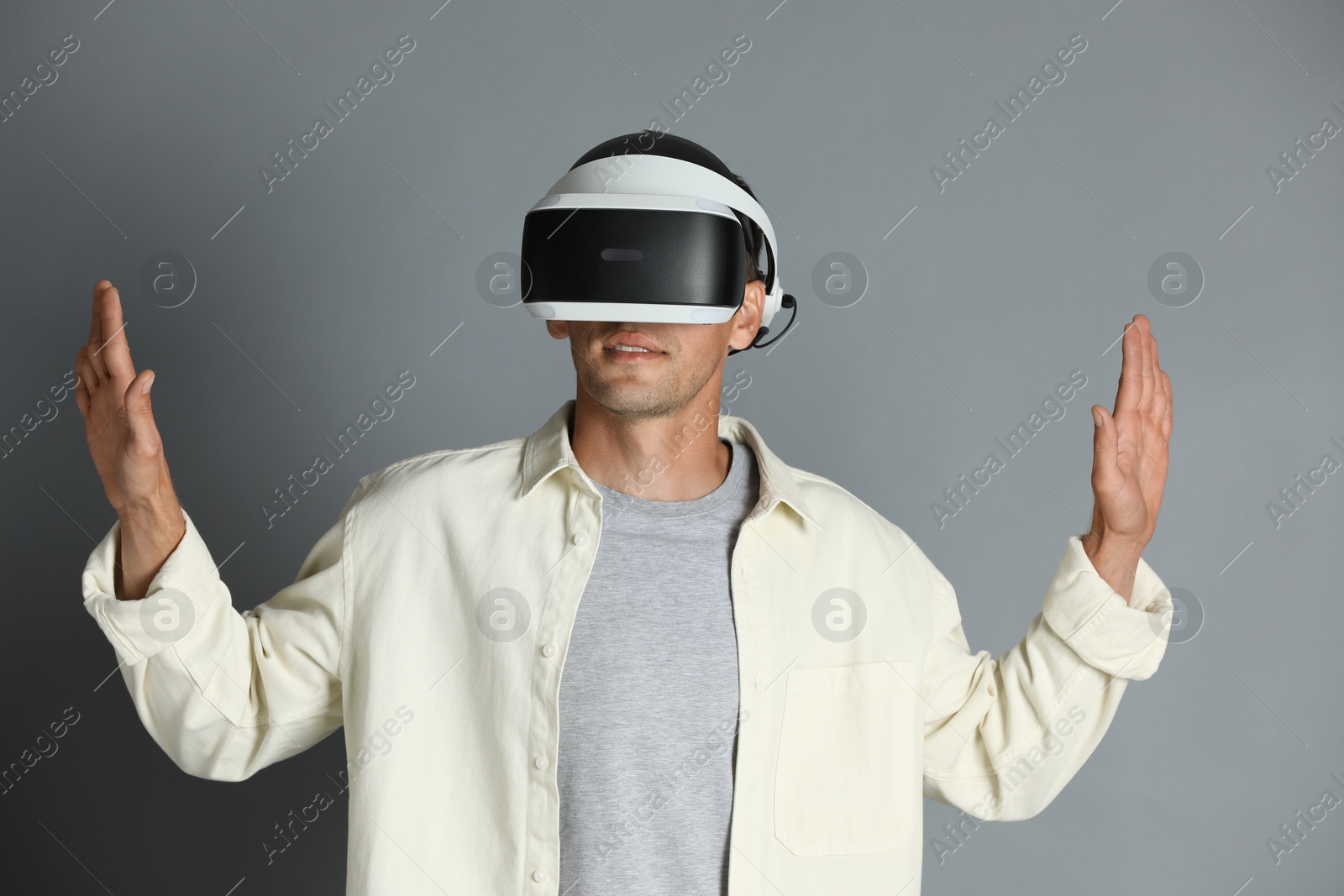 Photo of Man using virtual reality headset on gray background