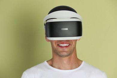 Photo of Smiling man using virtual reality headset on light green background