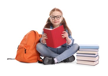 Cute little girl with stack of books and backpack on white background